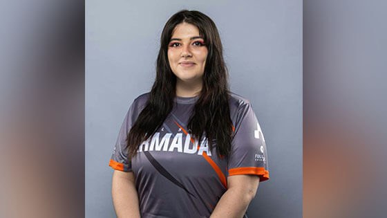 Brittanny MacCleod stands against a gray background and smiles. She has long brown hair and is wearing a gray Armada jersey.